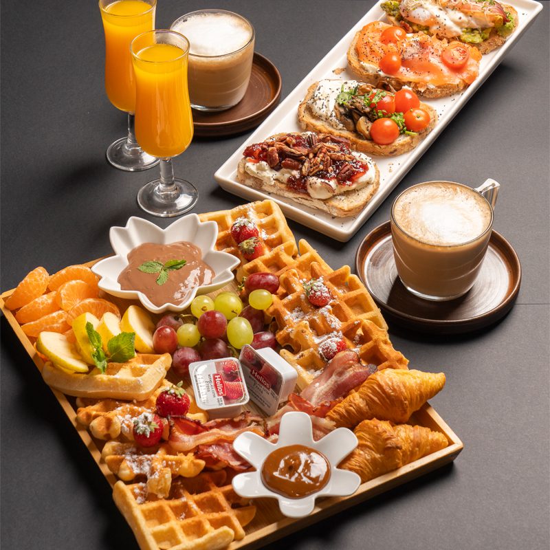 Tabla de waffles artesanales con toppings encantados y bebidas.
