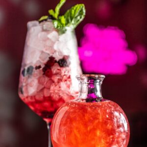 Cóctel Amor de Serendipia, con humo rosa, frutos rojos, lavanda y ginebra en una copa mágica que encierra un hechizo de corazón.