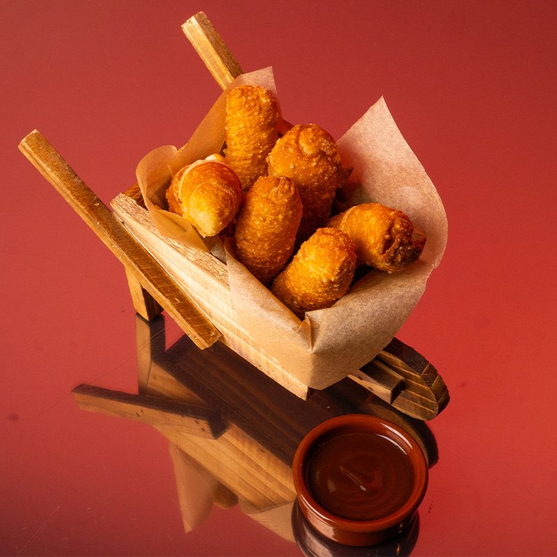 Tequeños dorados rellenos de queso fundido.