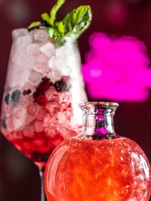 Cóctel Amor de Serendipia, con humo rosa, frutos rojos, lavanda y ginebra en una copa mágica que encierra un hechizo de corazón.