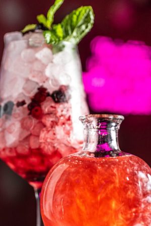 Cóctel Amor de Serendipia, con humo rosa, frutos rojos, lavanda y ginebra en una copa mágica que encierra un hechizo de corazón.