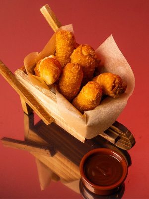 Tequeños dorados rellenos de queso fundido.