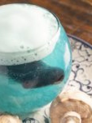 Poción Agua: cóctel de piña, flor azul y espuma cítrica. Una ola en copa que susurra secretos del mar con cada burbuja.