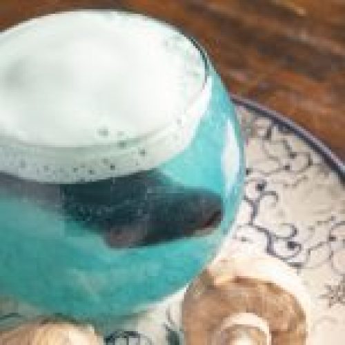 Poción Agua: cóctel de piña, flor azul y espuma cítrica. Una ola en copa que susurra secretos del mar con cada burbuja.